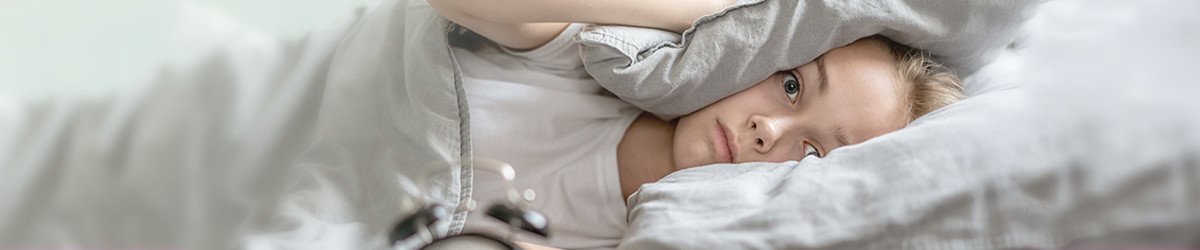 woman using pillow like ear muffs for sleeping